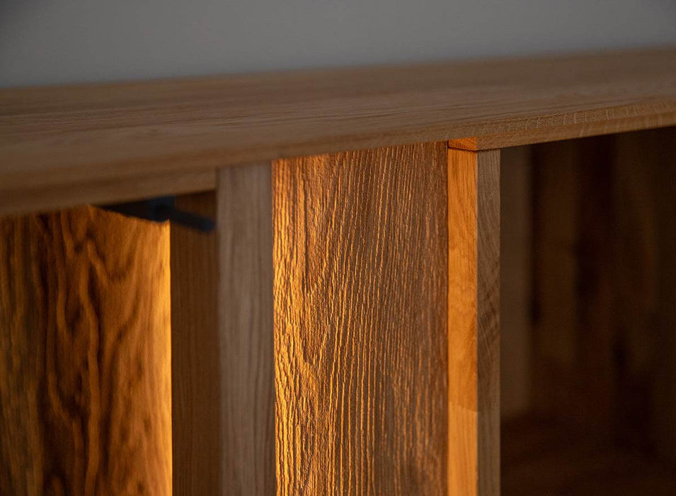 Beleuchtete Vitrinen Kommode Collodi aus massiver Eiche mit Rückwand in grober Holzstruktur -