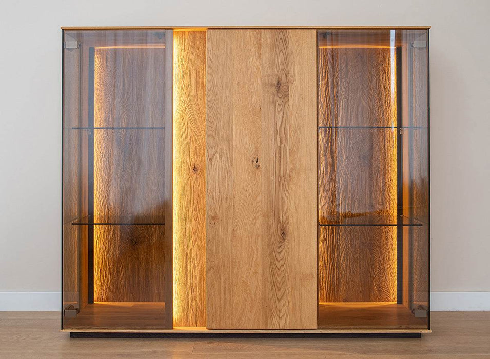 Beleuchtete Vitrinen Kommode Collodi aus massiver Eiche mit Rückwand in grober Holzstruktur -