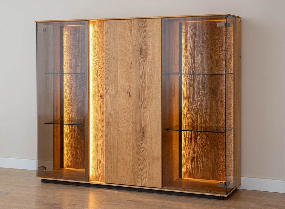 Beleuchtete Vitrinen Kommode Collodi aus massiver Eiche mit Rückwand in grober Holzstruktur -
