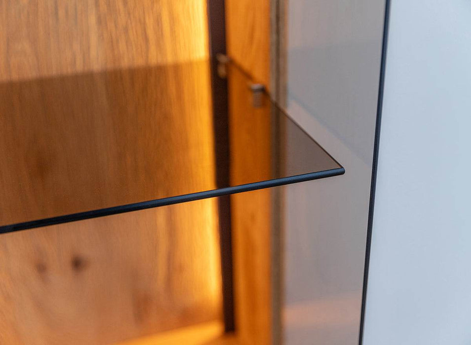 Beleuchtete Standvitrine Collodi aus massiver Eiche mit Rückwand in grober Holzstruktur -