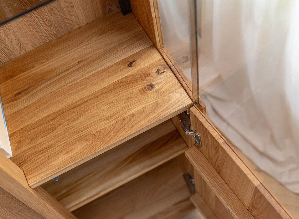 Beleuchtete Standvitrine Collodi aus massiver Eiche mit Rückwand in grober Holzstruktur -