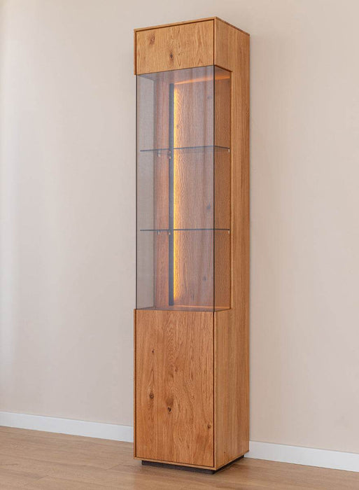 Beleuchtete Standvitrine Collodi aus massiver Eiche mit Rückwand in grober Holzstruktur -