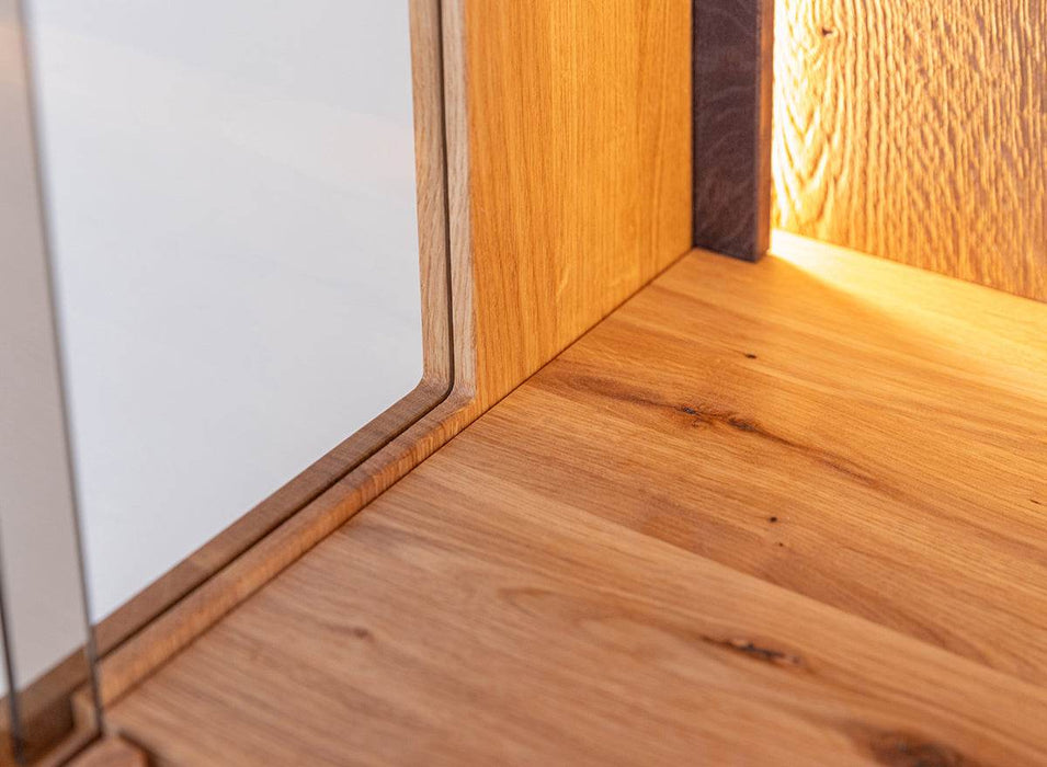 Beleuchtete Standvitrine Collodi aus massiver Eiche mit Rückwand in grober Holzstruktur -