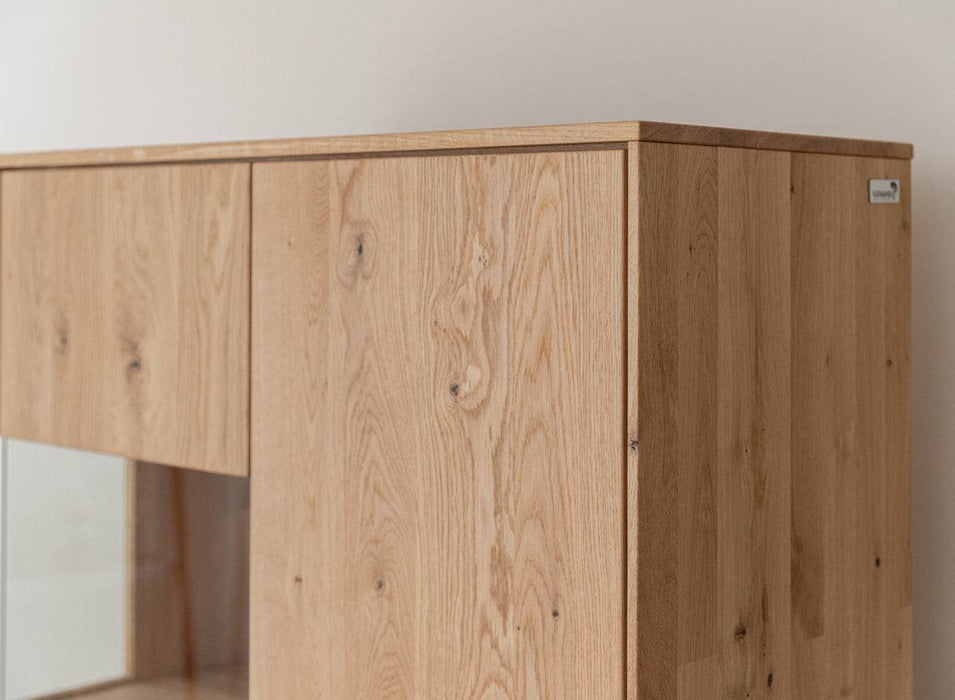 Beleuchtete Standvitrine aus massiver Eiche mit Lamellen | Wohnzimmerschrank Tirano II mit Rückwand in grober Holzstruktur -