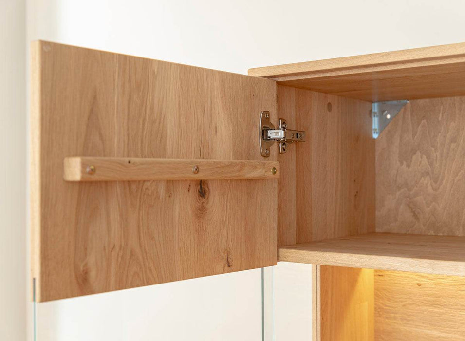 Beleuchtete Standvitrine aus massiver Eiche mit Lamellen | Wohnzimmerschrank Tirano II mit Rückwand in grober Holzstruktur -
