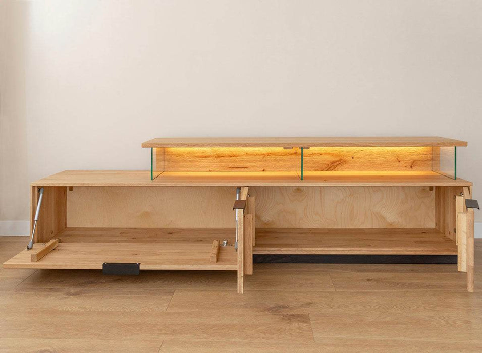 Beleuchtete Hängekommode aus massiver Eiche | TV-Board Tirano I mit Schaukasten und grober Holzstruktur -