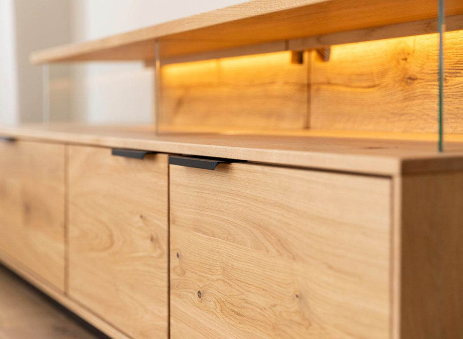 Beleuchtete Hängekommode aus massiver Eiche | TV-Board Tirano I mit Schaukasten und grober Holzstruktur -