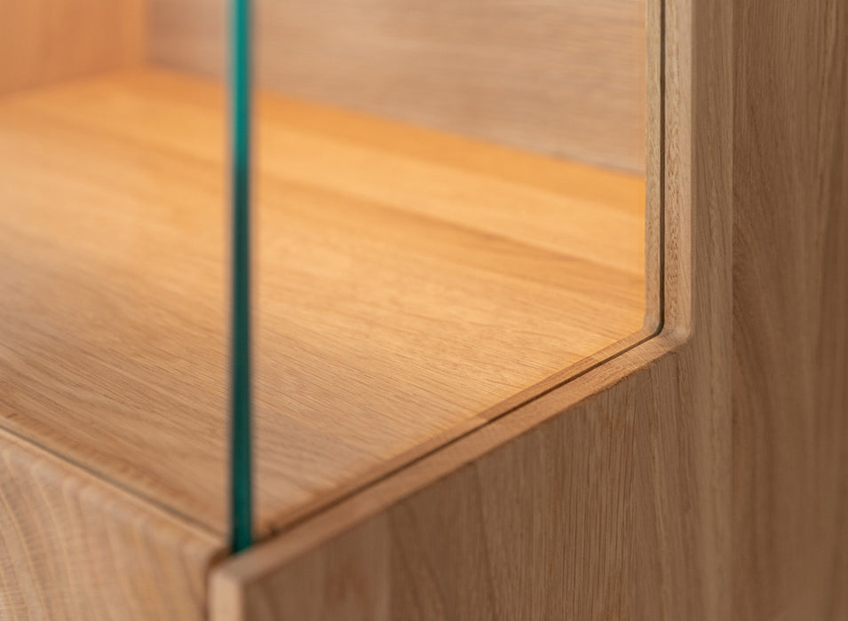 Beleuchtete Hängevitrine aus massiver Eiche mit Lamellen | Vitrine Tirano II mit Rückwand in grober Holzstruktur