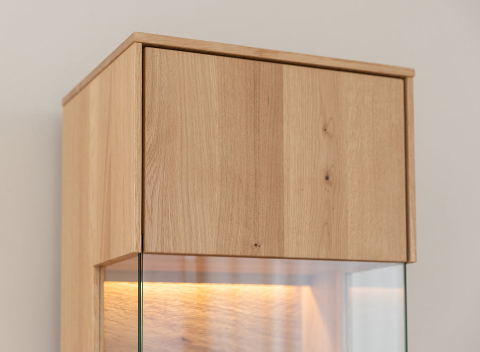 Beleuchtete Hängevitrine aus massiver Eiche | Vitrine Tirano I mit Rückwand in grober Holzstruktur