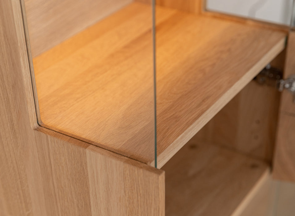 Beleuchtete Hängevitrine aus massiver Eiche mit Lamellen | Vitrine Tirano II mit Rückwand in grober Holzstruktur