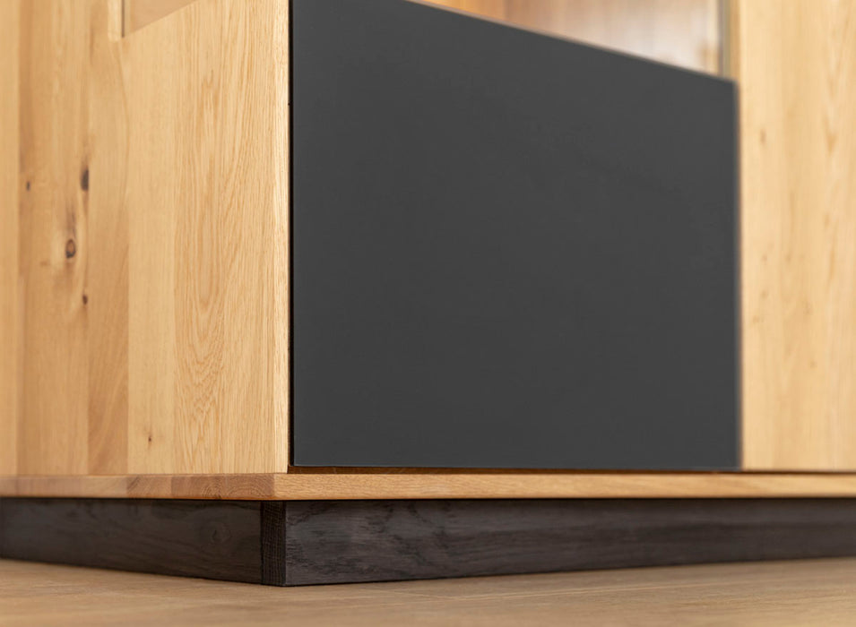 Beleuchtete Standvitrine aus massiver Eiche und Glas | Wohnzimmerschrank Tirano IV mit Rückwand in grober Holzstruktur