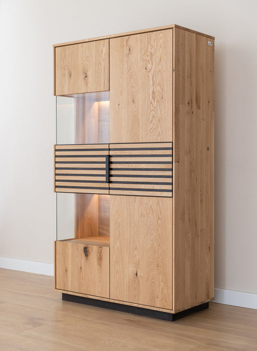 Beleuchtete Standvitrine aus massiver Eiche mit Lamellen | Wohnzimmerschrank Tirano II mit Rückwand in grober Holzstruktur