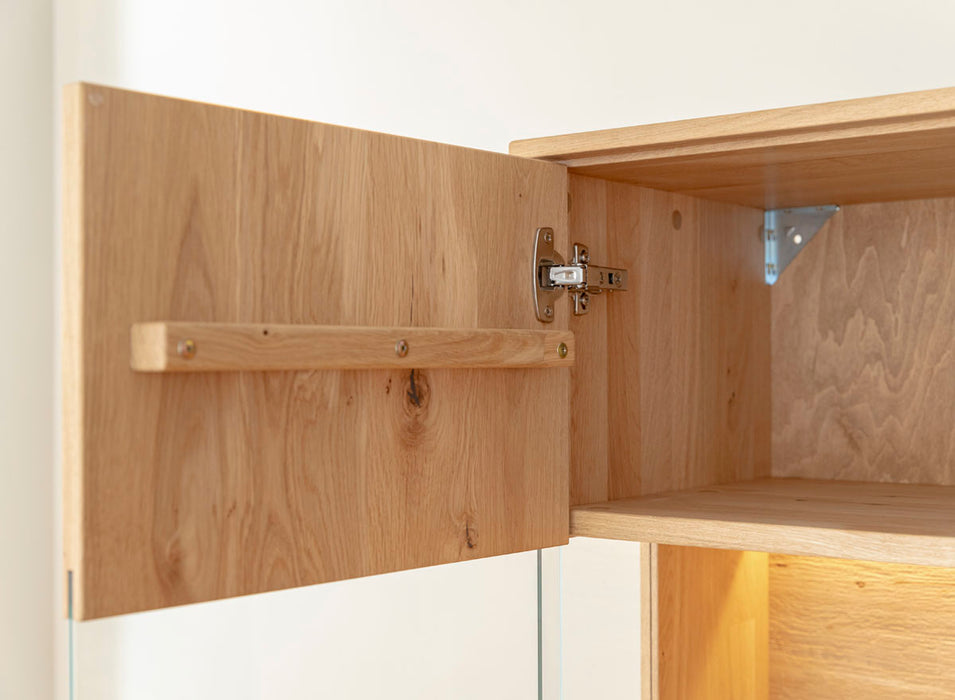 Beleuchtete Standvitrine aus massiver Eiche mit Lamellen | Wohnzimmerschrank Tirano II mit Rückwand in grober Holzstruktur