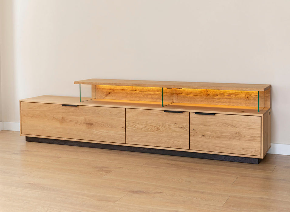 Beleuchtete Hängekommode aus massiver Eiche | TV-Board Tirano I mit Schaukasten und grober Holzstruktur