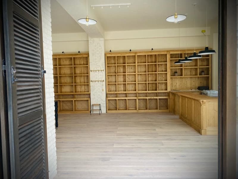 Blick-in-Verkaufsraum-Fensterlaeden-lamellen-Wandregale-Empfangstheke-Pendelleuchten