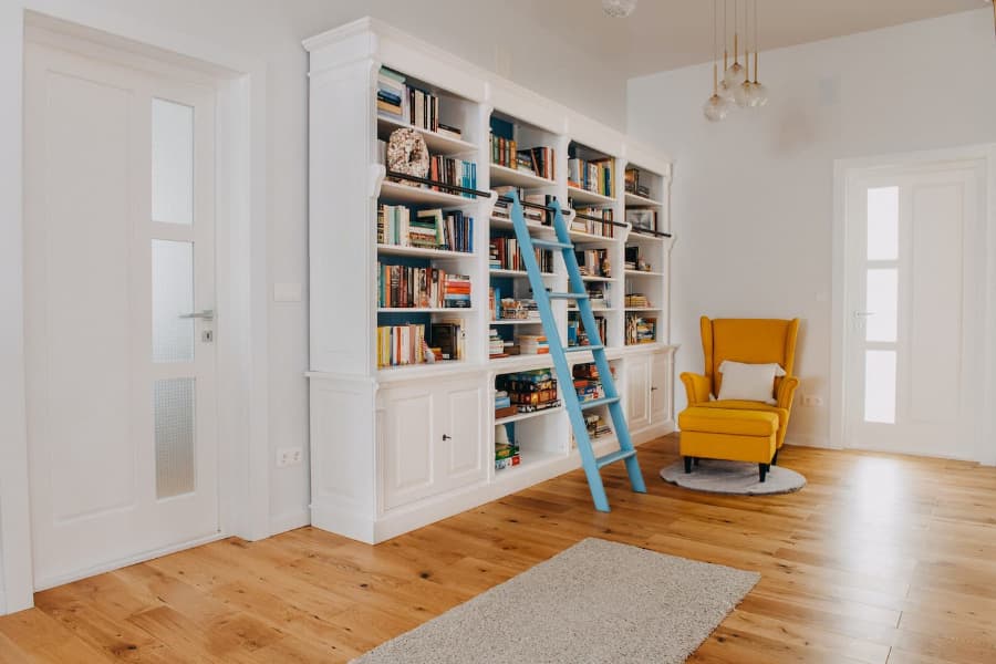 großer-Buecherschrank-bibliothekschrank-Massivholz-weiß-mit-blauer-Leiter-Sofa-Gelb-Haengeleuchte